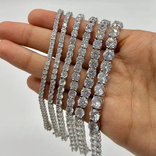 A hand holding several diamond tennis bracelets fanned out